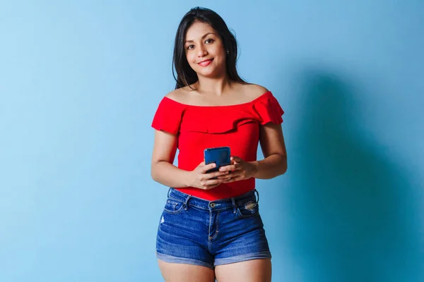 Una Joven Latina Usando Smartphone Sobre Fondo Azul Aislado — Foto de Stock