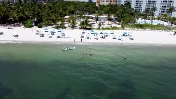 Szerokie ujęcie ludzi spacerujących po plaży z górami w oddali w ciągu dnia — Wideo stockowe