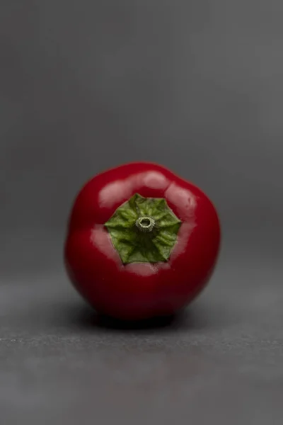 小さな赤い活気に満ちたカラフルな唐辛子にスポットライトを当て垂直フレーム滑らかな反射性の赤い皮と緑のトップ — ストック写真