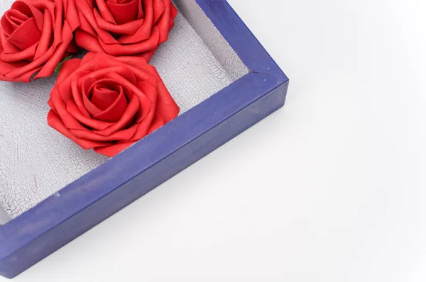 一个蓝色的木制盒子 白色背景上有三朵红玫瑰 文字空间 — 图库照片