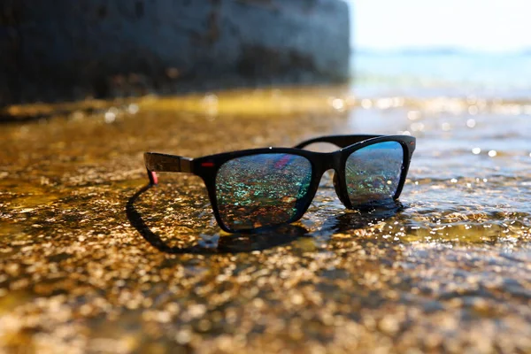 Płytkie Ujęcie Ostrości Klasycznej Pary Okularów Przeciwsłonecznych Wodzie Plaży Słonecznym — Zdjęcie stockowe