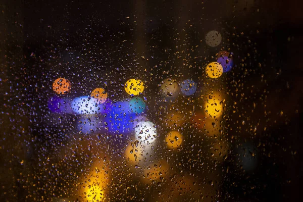 一个被雨滴覆盖的窗户的特写镜头 背景暗而模糊 灯光昏暗 — 图库照片