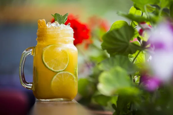 美しい花と木製の表面にマソン瓶の中に冷たいフルーツティーのクローズアップショット — ストック写真