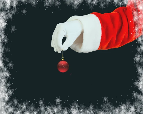 Die Hand Des Weihnachtsmannes Hält Einen Baumschmuck Auf Schwarzem Hintergrund — Stockfoto