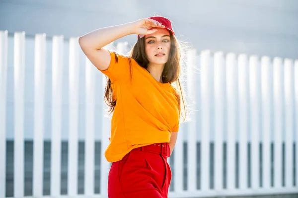 一个穿着红帽子和裤子的年轻时髦女人摆姿势 — 图库照片