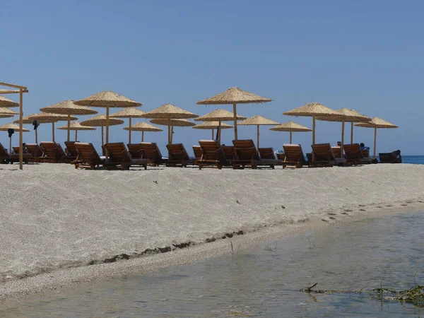 海滩上稻草雨伞下木制长椅的精美特写 — 图库照片