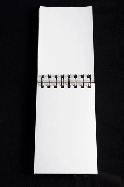 黒い背景に隔離された開いた螺旋状のノートブックの垂直クローズアップショット — ストック写真