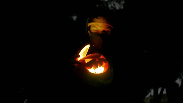 一个男人拿着一个火热的南瓜和一个雕刻的脸作为万圣节的象征 — 图库照片