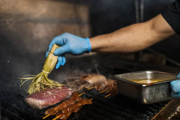 料理人はグリルの肉の上にスパイスを磨く — ストック写真