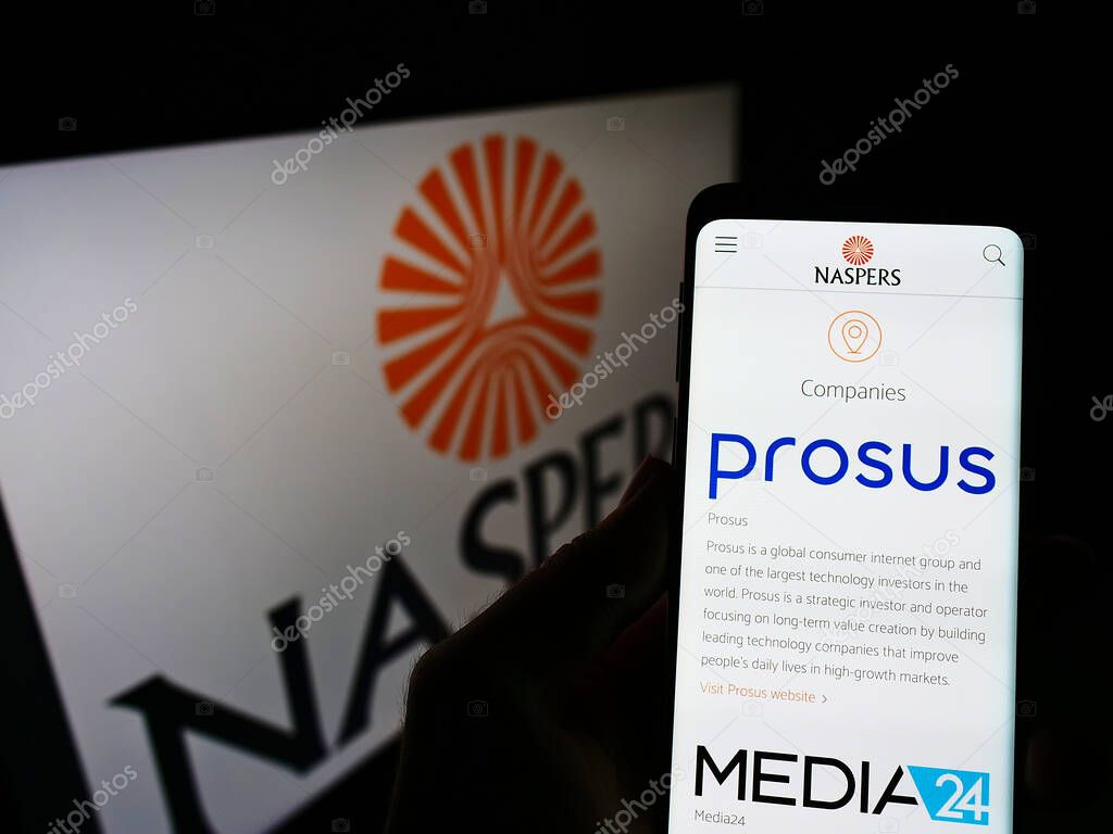STUTTGA, GERMANY - Aug 02, 2021: Person holding cellphone with webpage of conglomerate Naspers Limited on screen in front of logo. Focus on center of phone display.