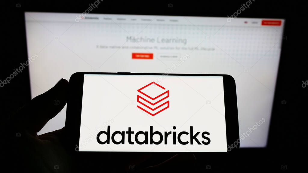 STUTTGART, GERMANY - Aug 13, 2021: Person holding mobile phone with logo of US company Databricks Inc. on screen in front of web page. Focus on phone display.