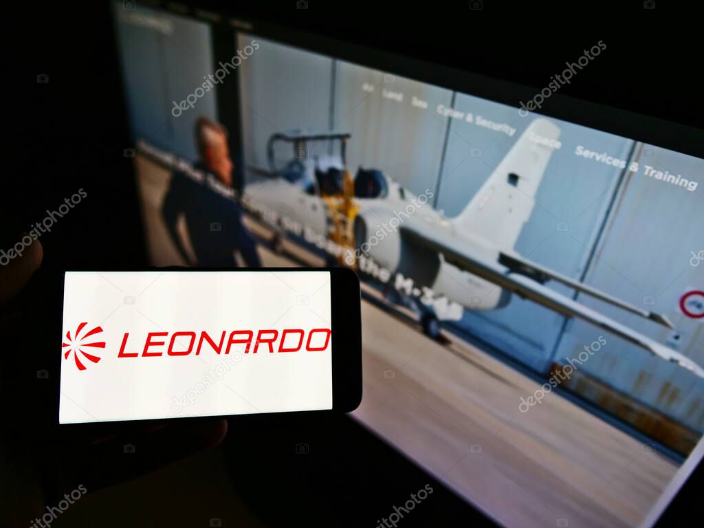 STUTTGART, GERMANY - Feb 10, 2021: Person holding mobile phone with logo of defense company Leonardo S.p.A. on screen in front of webpage. Focus on cellphone display.