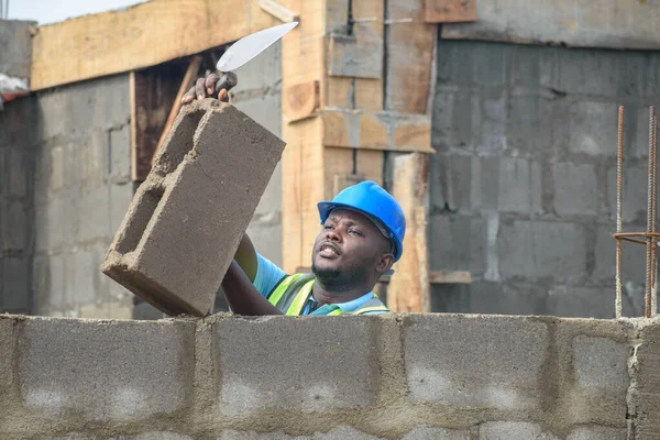 An African construction worker wearing the reflective jacket while working on a building site