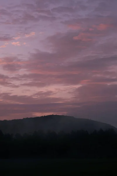 Eine Silhouette Von Bäumen Und Bergen Unter Einem Sonnenuntergang — Stockfoto