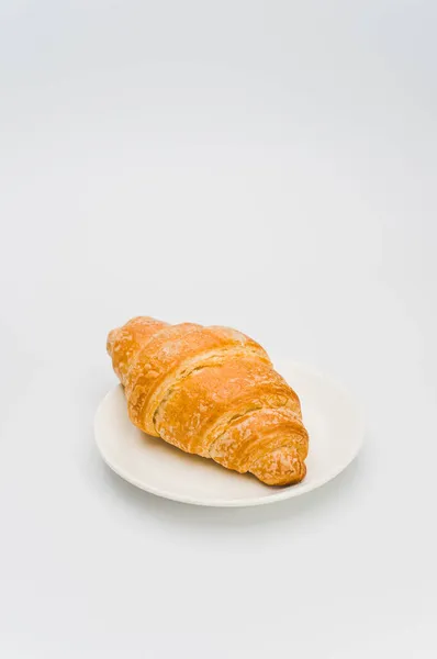 Shot Van Verse Boterachtige Croissant Een Bord Een Witte Achtergrond — Stockfoto