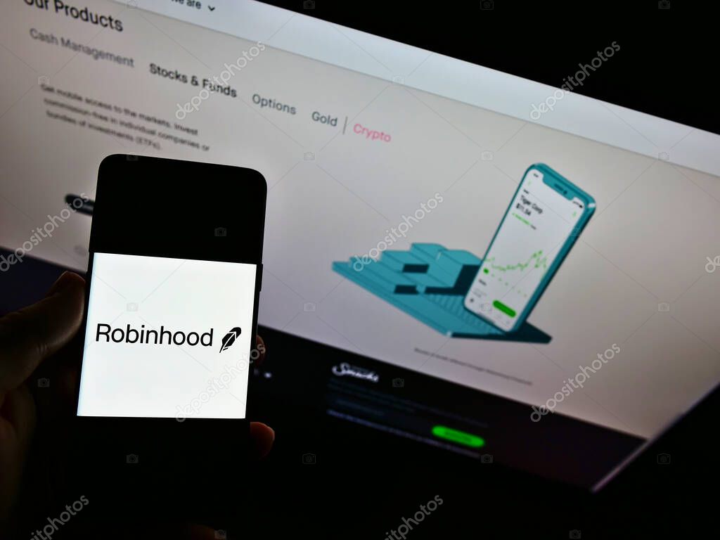 STUTTGART, GERMANY - Feb 01, 2021: Person holding mobile phone with logo of company Robinhood Markets Inc. on display in front of website. Focus on phone screen.