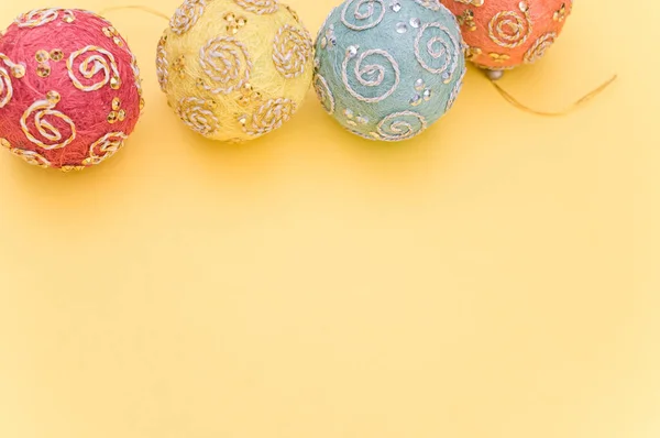 黄色の表面にテキストのためのスペースを持つ多色のクリスマスの装飾ボール — ストック写真