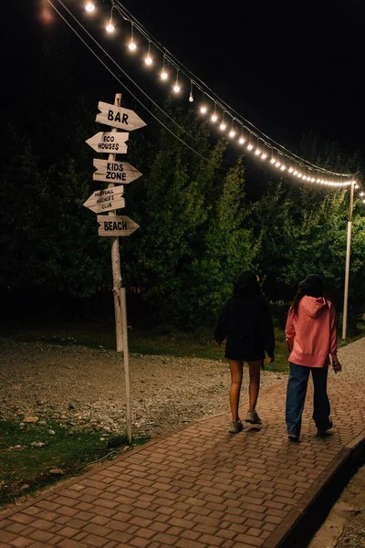 Visszapillantás Két Lányra Akik Parkban Sétálnak Fehér Fából Készült Vezetőtábla — Stock Fotó