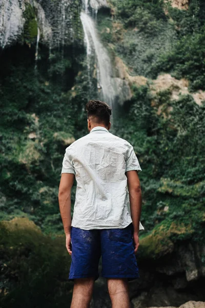 一个男人站在瀑布前的垂直镜头 — 图库照片