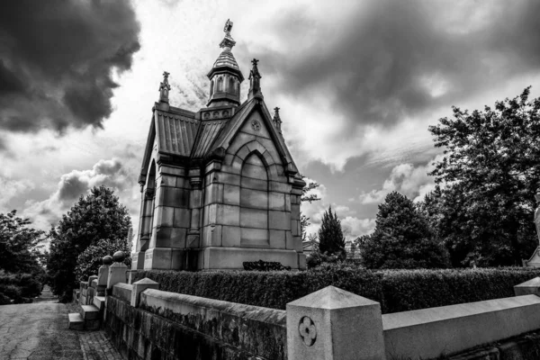 曇った空に対する墓地の石の墓のグレースケールショット — ストック写真