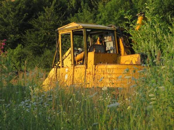 森の近くの畑の古い黄色の掘削機 — ストック写真