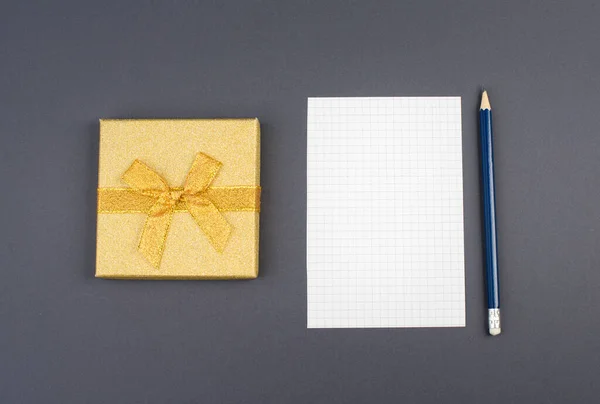 Leeg Papier Een Pen Een Goudkleurig Cadeau Een Donkergrijze Achtergrond — Stockfoto