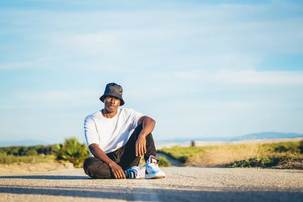 Young Black Handsome Man Wearing Bucket Hat Sitting Ground Middle — стоковое фото