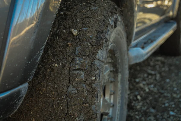Tire covered in rocks and mud on off-road trail
