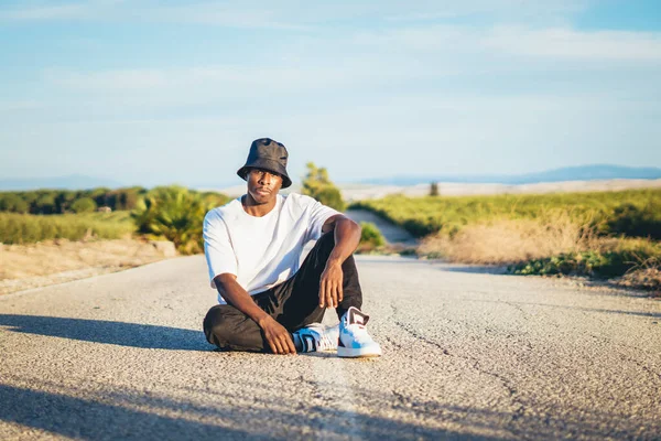 Young Black Handsome Man Wearing Bucket Hat Sitting Ground Middle — стоковое фото