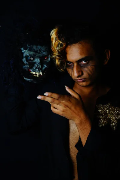 恐ろしいマスクの横に彼の手で指している南アジアの男性のクローズアップショット — ストック写真