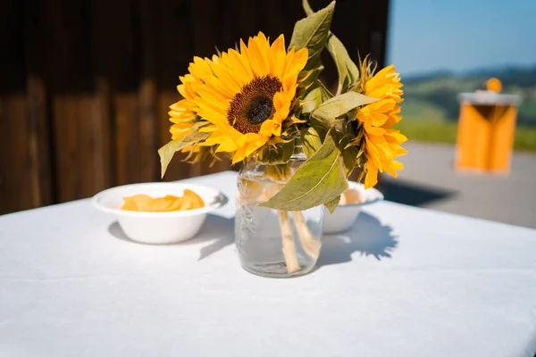 在室外的桌子上 在阳光下 玻璃瓶里有一束美丽的黄色向日葵 这是一张特写 — 图库照片