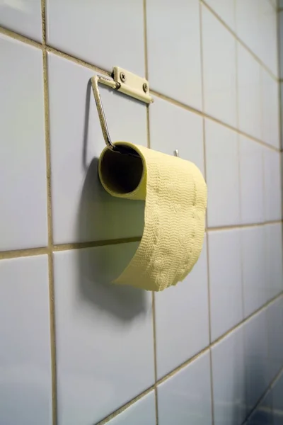 公衆トイレのタイル壁に黄色いトイレットペーパーのロール — ストック写真