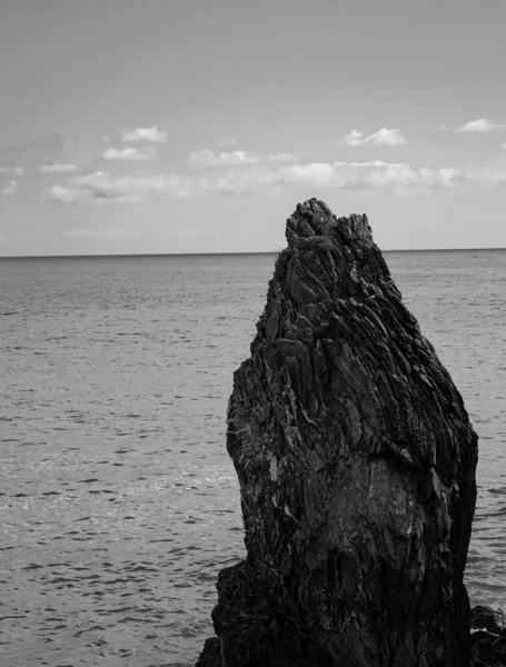 一片灰色的岩石 背景是海水 背景是多云的天空 — 图库照片