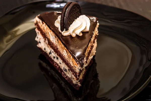 黒の皿の上にオレオを乗せたチョコレートムースデザートケーキのクローズ 料理のコンセプト — ストック写真