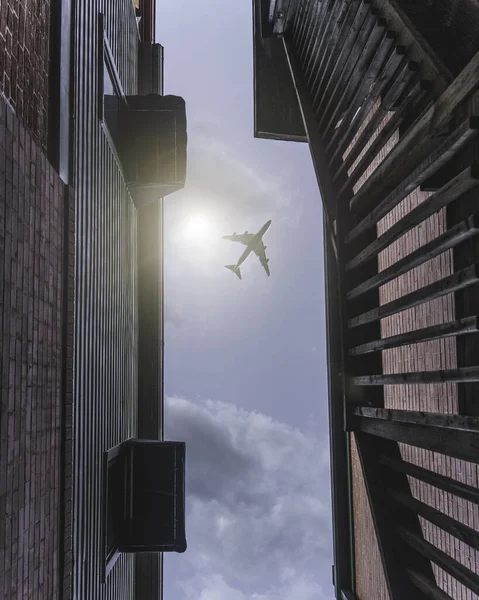 在建筑物之间的晴空中飞行的飞机的垂直照片 — 图库照片