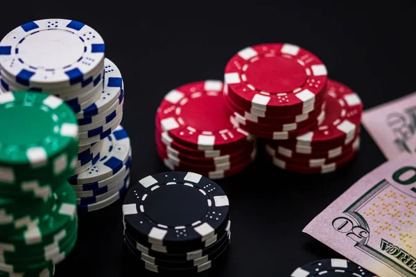 A closeup of cash dollar bills and stacks of poker chips placed on the poker table; gambling concept