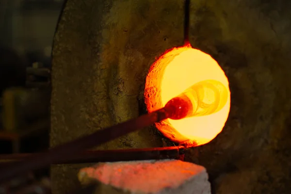 A closeup of melting glass in a workshop with a dark blurry background