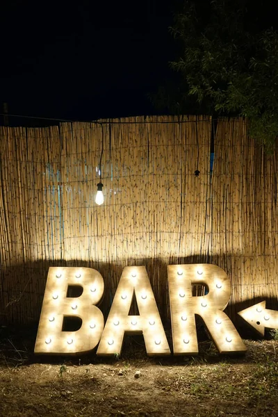 Colpo Verticale Segno Illuminato Bar Appoggiato Una Parete Foglie Palma — Foto Stock