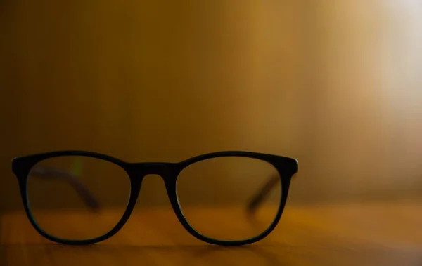 Egy Közeli Felvétel Fekete Szemüvegekről Egy Fából Készült Asztalon Homályos — Stock Fotó