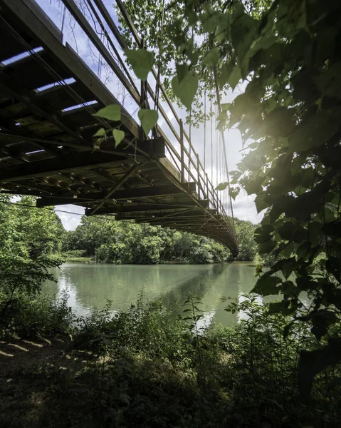 Tiro Vertical Uma Ponte Suspensa Sobre Lago Cercado Por Árvores — Fotografia de Stock