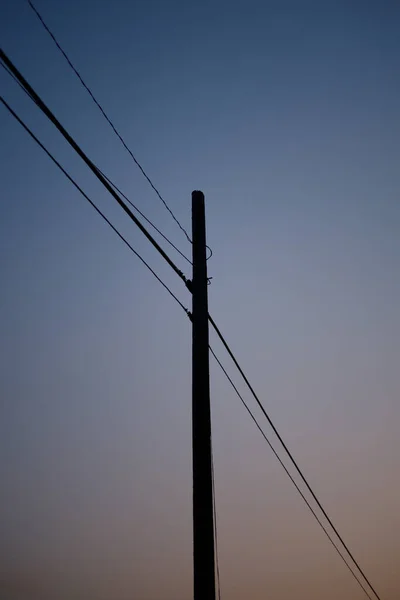日没の空に木製の電柱の垂直ショット — ストック写真