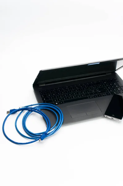 Como Italy 2021年10月31日 带有闭盖智能手机的笔记本电脑和带有文字空间的白色工作台上的网络电缆 — 图库照片