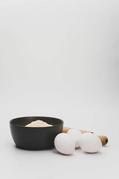 Nudelholz Weiße Eier Und Dunkelgraue Schüssel Mit Vollkornmehl Auf Weißem — Stockfoto