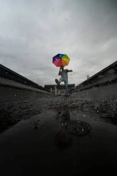 Человек Радужным Зонтиком Бьющим Воду Лужи — стоковое фото