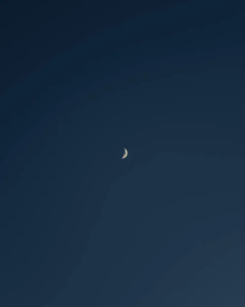 青い空に半分の月の垂直ショット — ストック写真