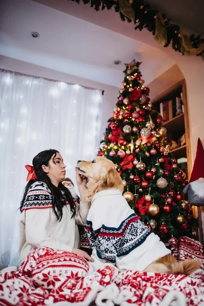 Жінка Грає Своїм Золотим Собакою Ретривером Біля Барвистої Різдвяної Ялинки — стокове фото