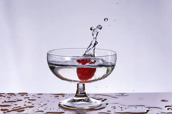 スプラッシュ付きの水のガラスに落ちるベリー — ストック写真