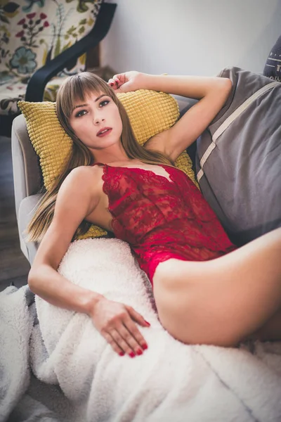 一个性感迷人的塞尔维亚女人穿着红色女士内衣睡衣躺在沙发上 — 图库照片