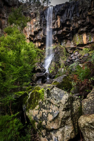 悬崖峭壁环绕的美丽瀑布的垂直镜头 — 图库照片