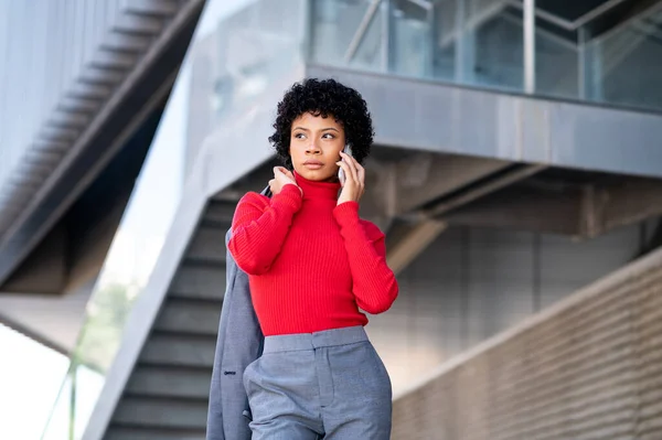 stock image A young African-American businesswoman wearing a red turtleneck and a suit talking on a phone